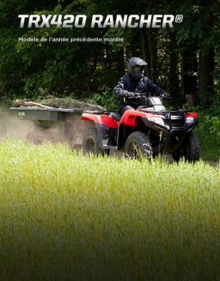 TRX420 Rancher. Taille modeste, personnalité flamboyante. Image d'un pilote de VTT qui manœuvre sur de gros rochers sur une piste accidentée en pente.