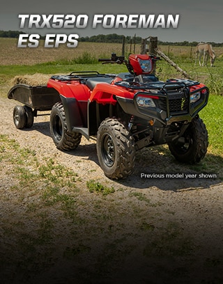 TRX500 Foreman ES EPS. The limitless legend. Image of orange ATV dramatically parked on gravel trail with majestic mountain peaks in background. 